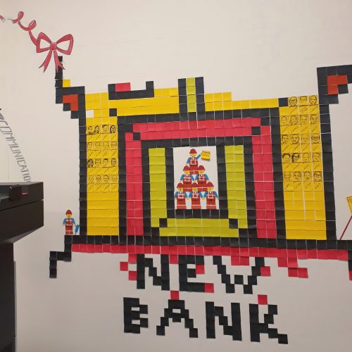 Illustration made from sticky notes, with staff's faces and values on the 'bricks' of the bank